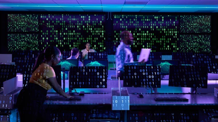 Professionals working at computers in a blue, backlit room 