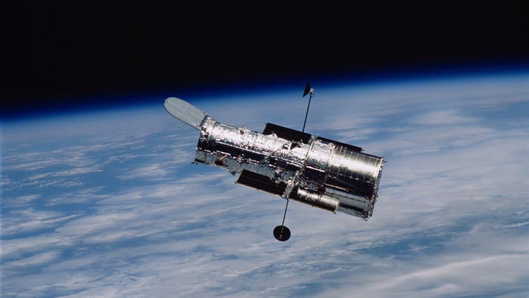 The Hubble Telescope floating in space above the Earth