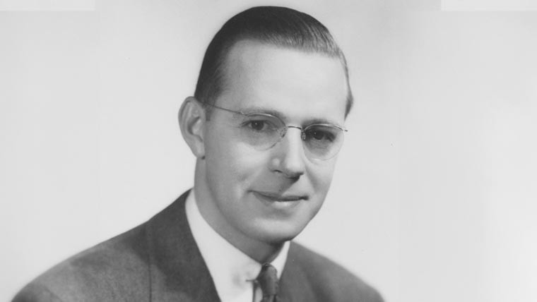 Black & white portrait of James Allen in a suit and glasses